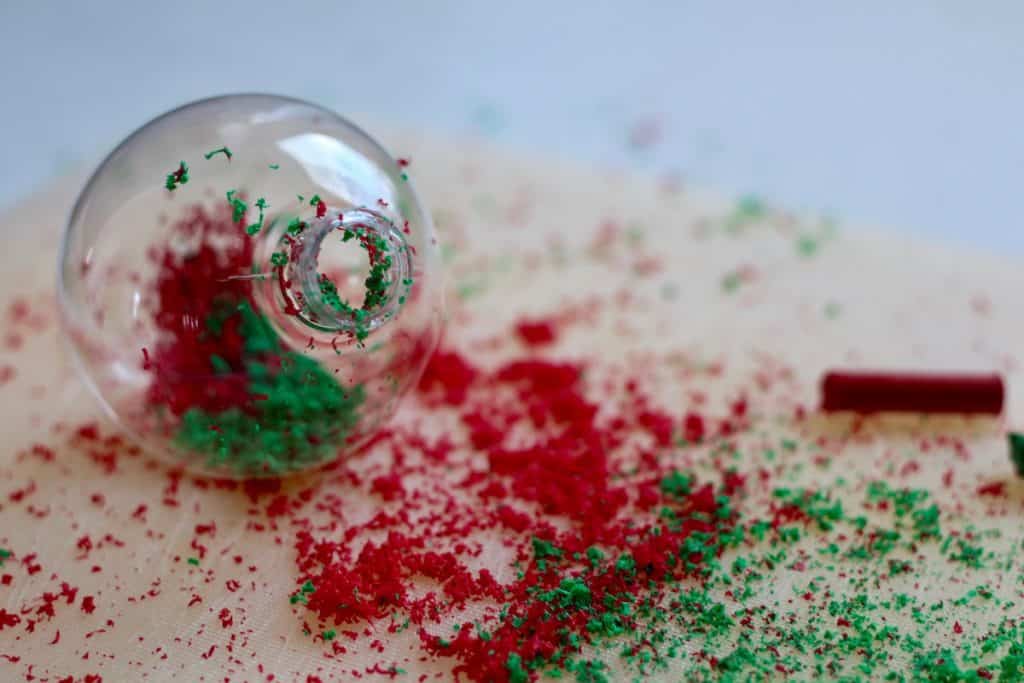 Fillable clear ornament with red and green crayon shavings in it