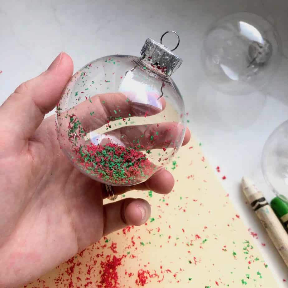 Fillable round Christmas tree ornament ball with red and green crayon shavings in it