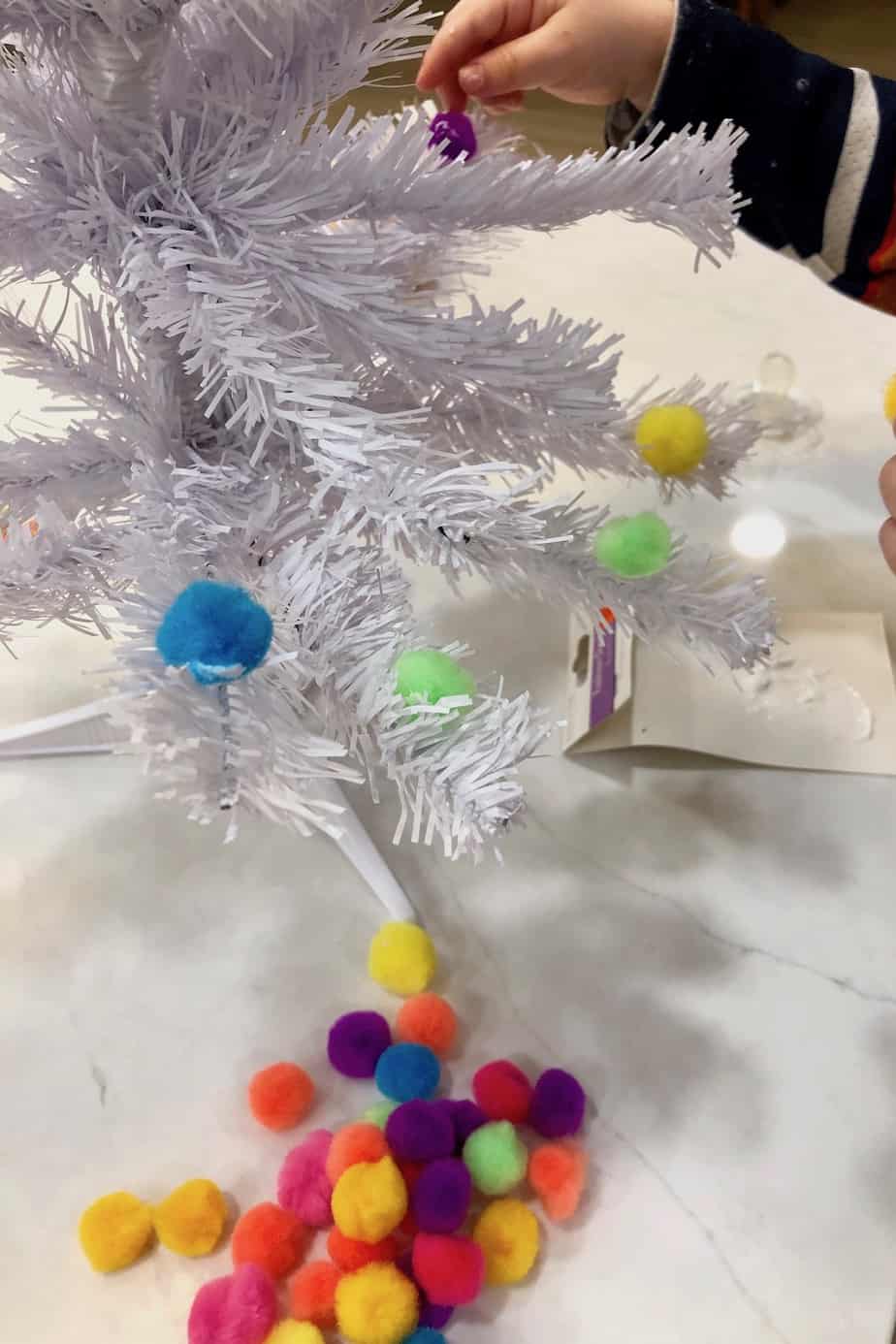 Gluing pom poms onto white faux mini christmas tree