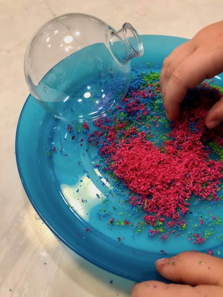 Pink crayon shavings on a blue plate for a Christmas craft