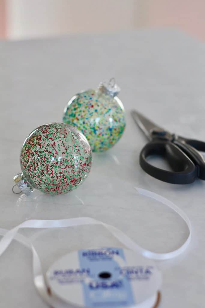 Tying a ribbon hanging loop onto the top of the finished crayon diy ornaments