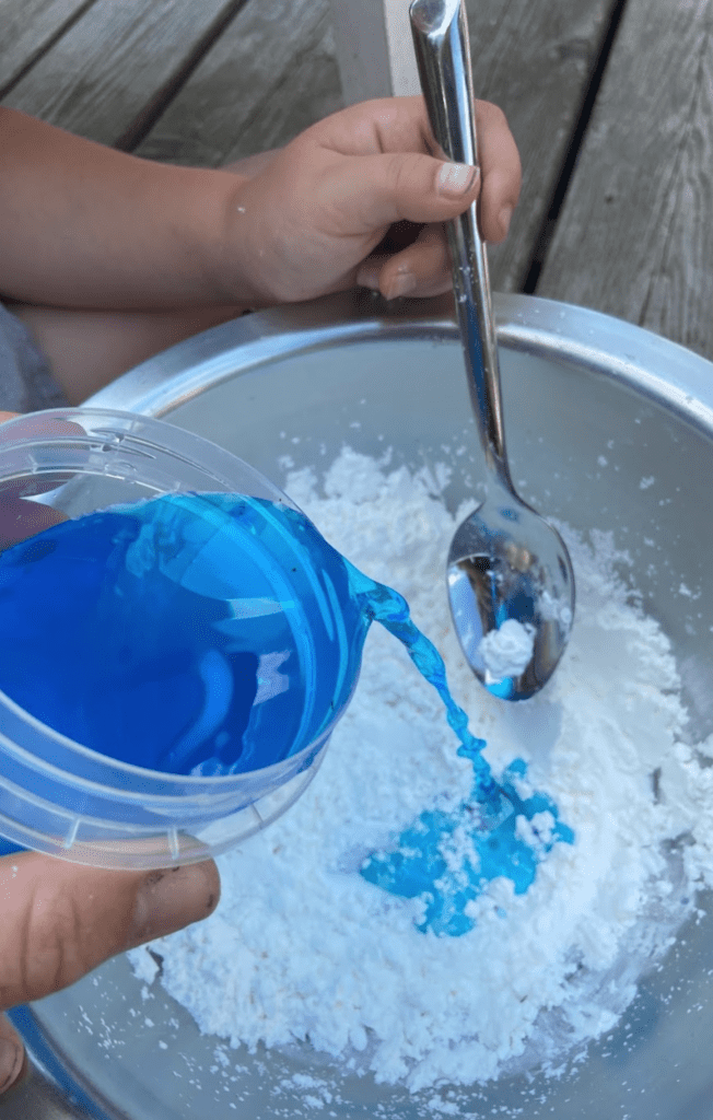 Pouring blue colored water into cornstarch