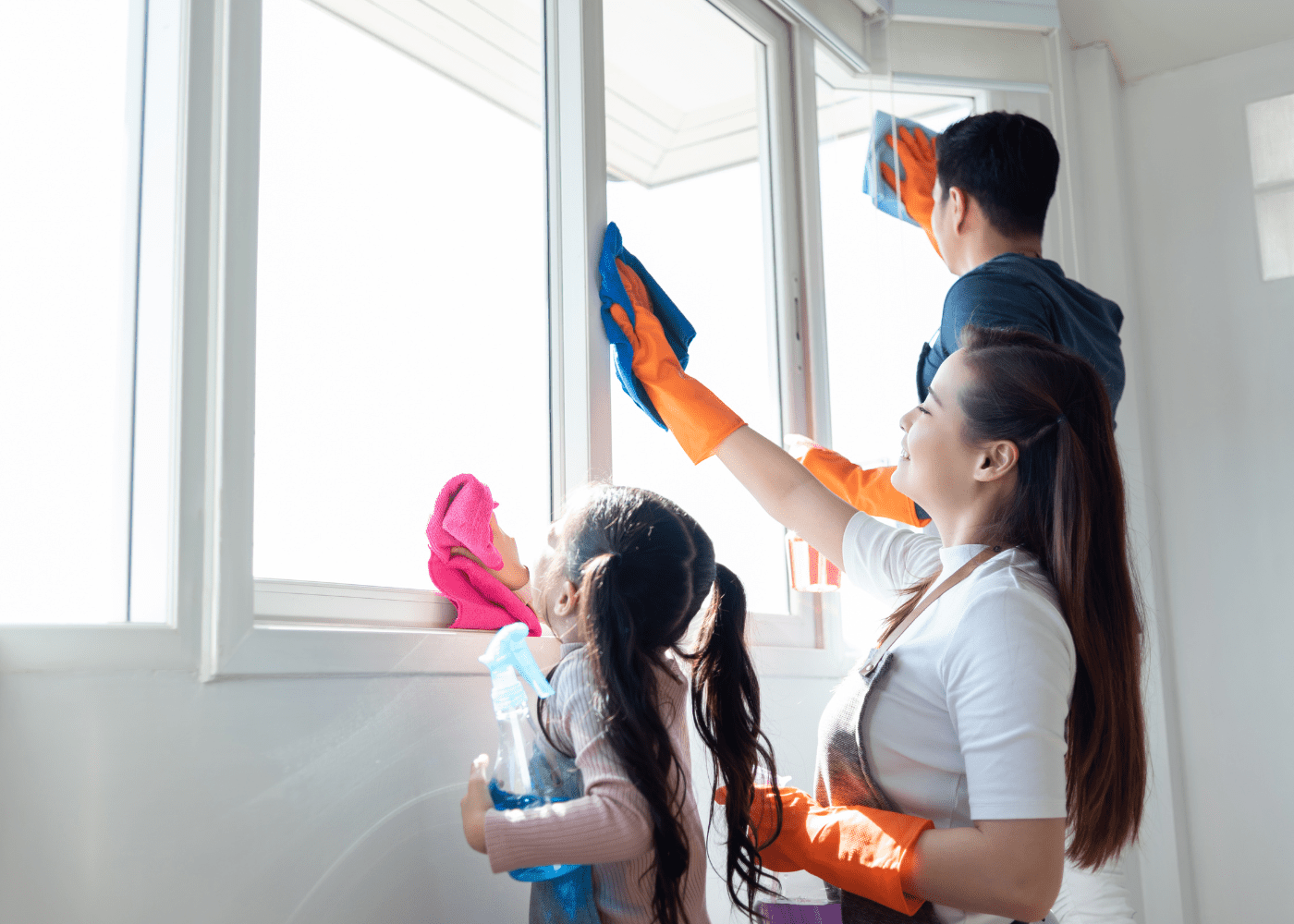 Family of three cleaning windows, including two adults and a child.