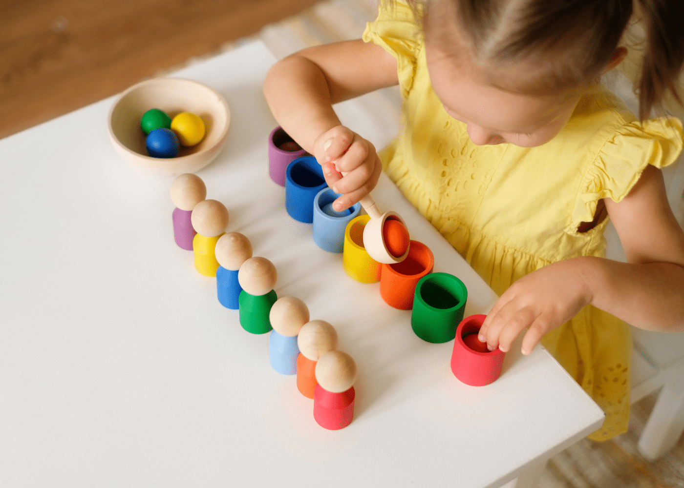 An example of simple preschool sorting activities you can do at home with a child sorting colored balls into matching colored cups.
