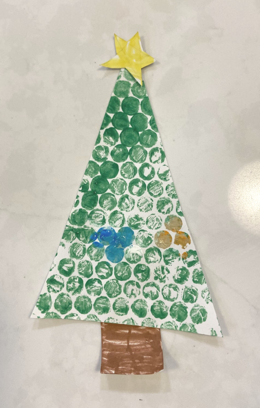 Paper tree decorated with green, blue, and cold dots. It also has a yellow star on the top.