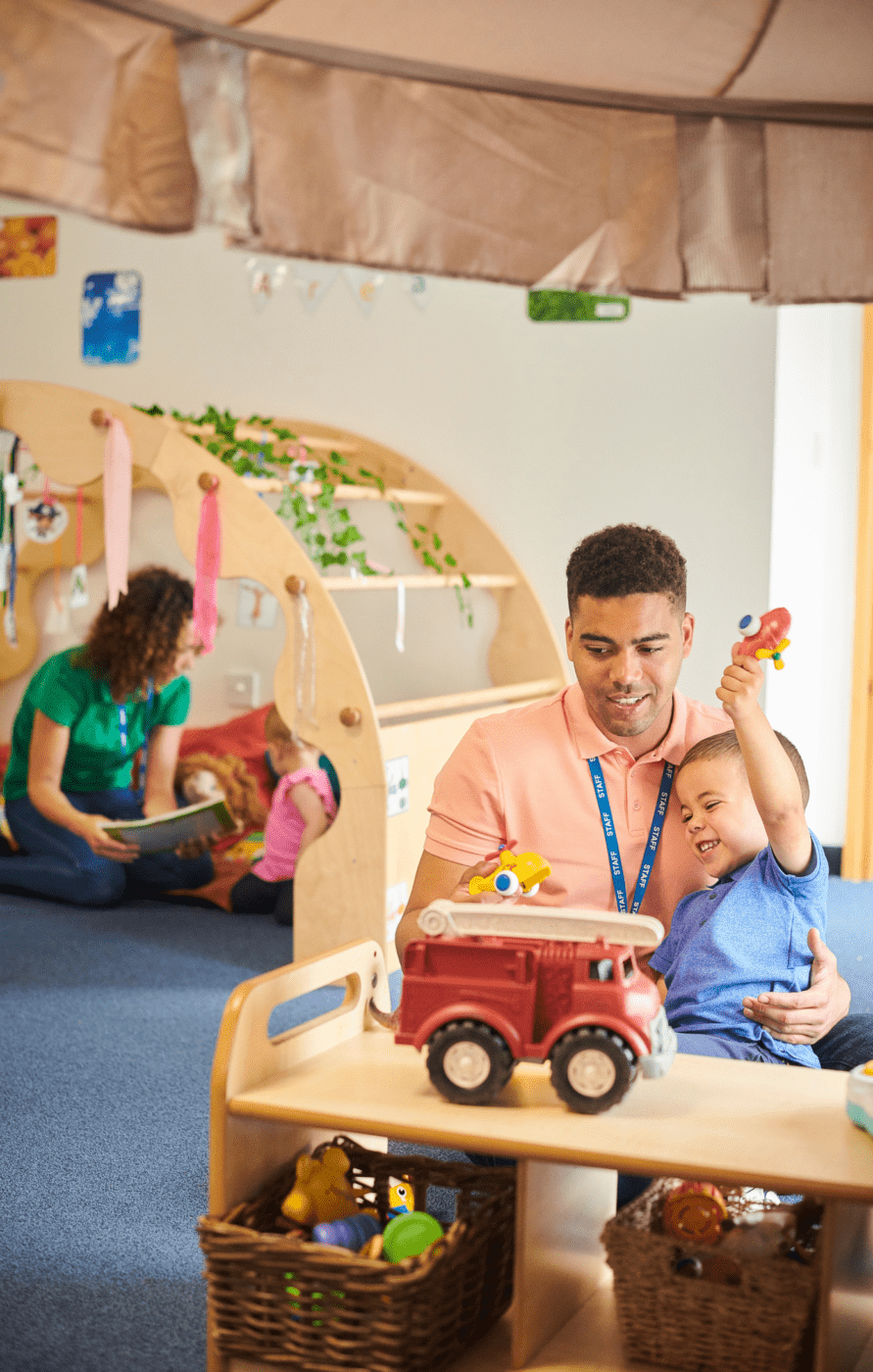 Child care providers working in a preschool. Pictued on the left is one worker reading to a child and on the right is one worker holding a child while paying with toy airplanes.