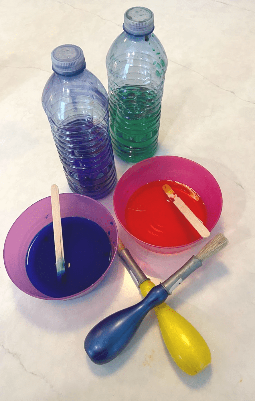 Materials for snow painting: Bottles with water and food coloring, and two paint brushes.