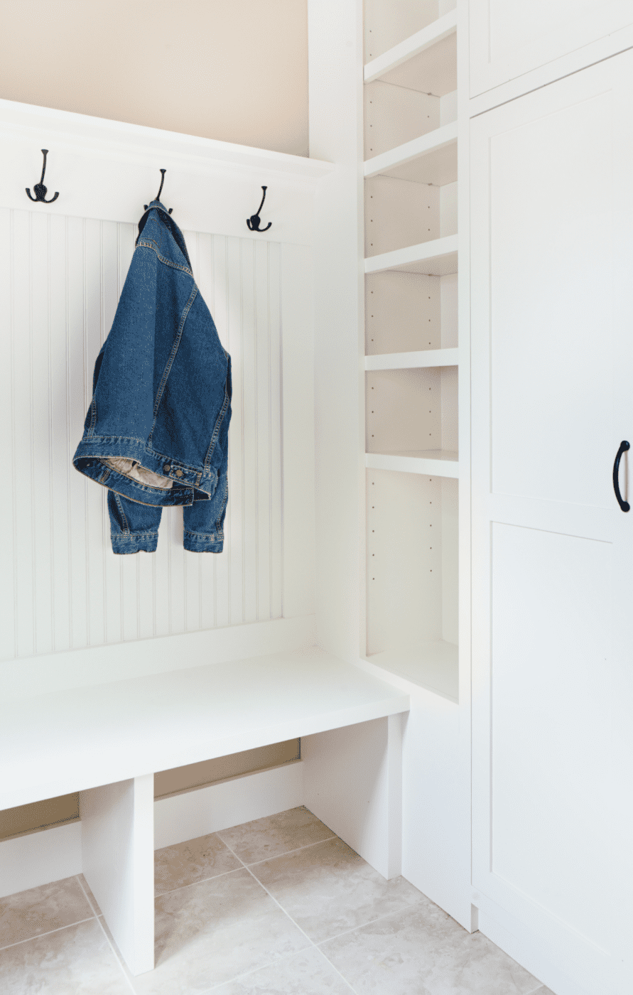 Denim jacket hanging on a wall hook in an entryway.