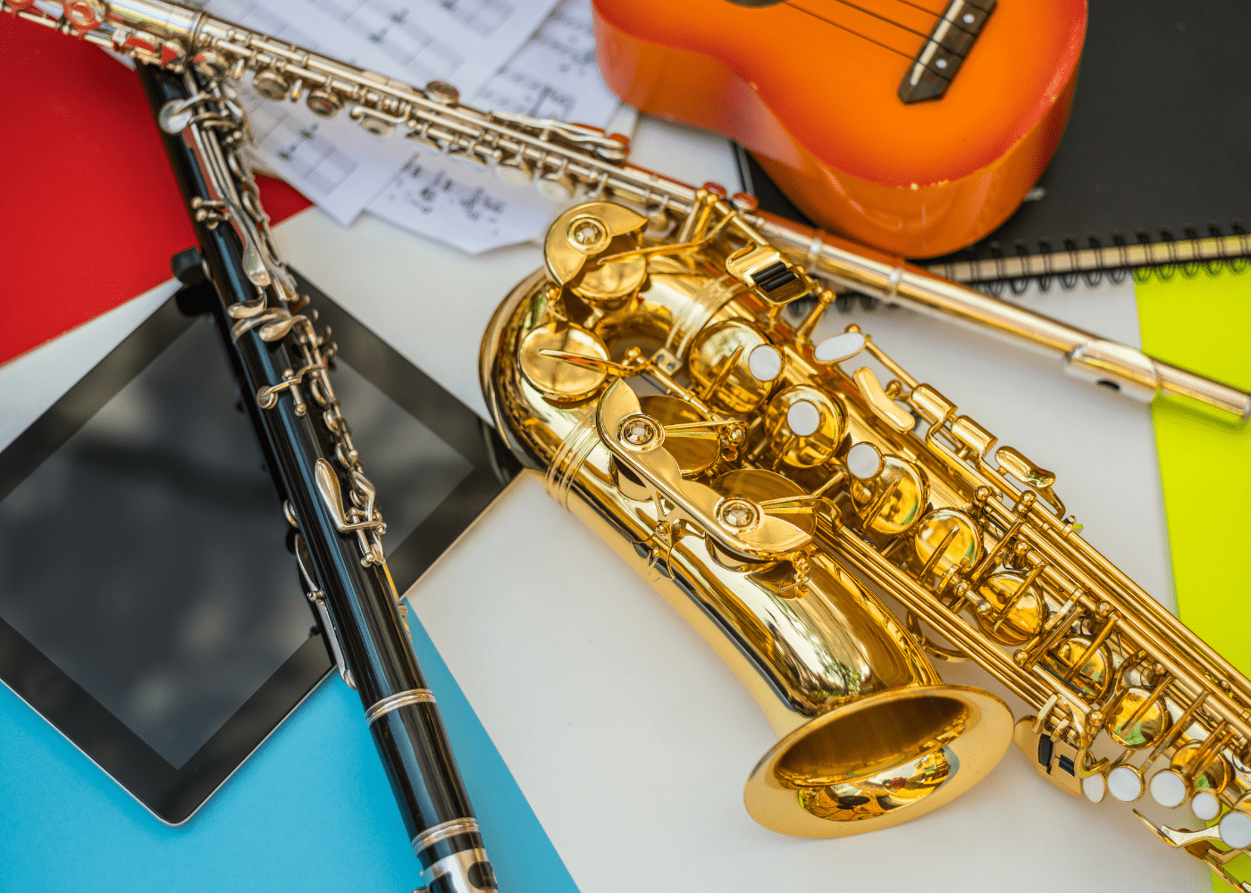 A collection of musical instruments, including a clarinet, saxophone, flute and ukulele.