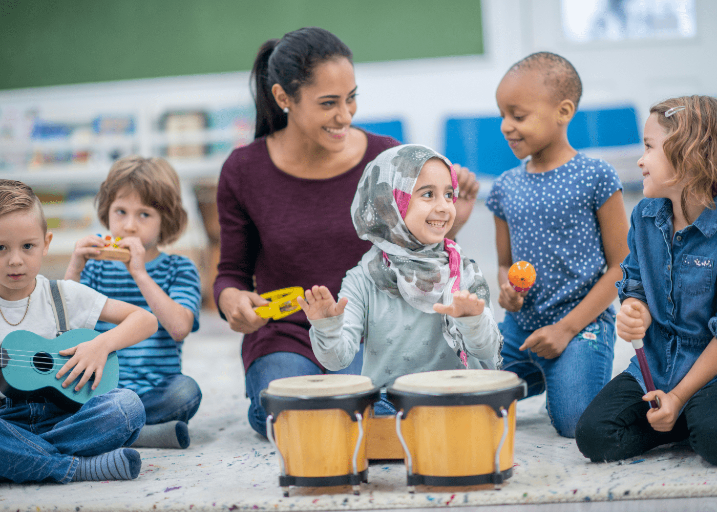 A photo of five children enjoying playing with musical instruments for kids, including a drum, ukulele, and maracas.