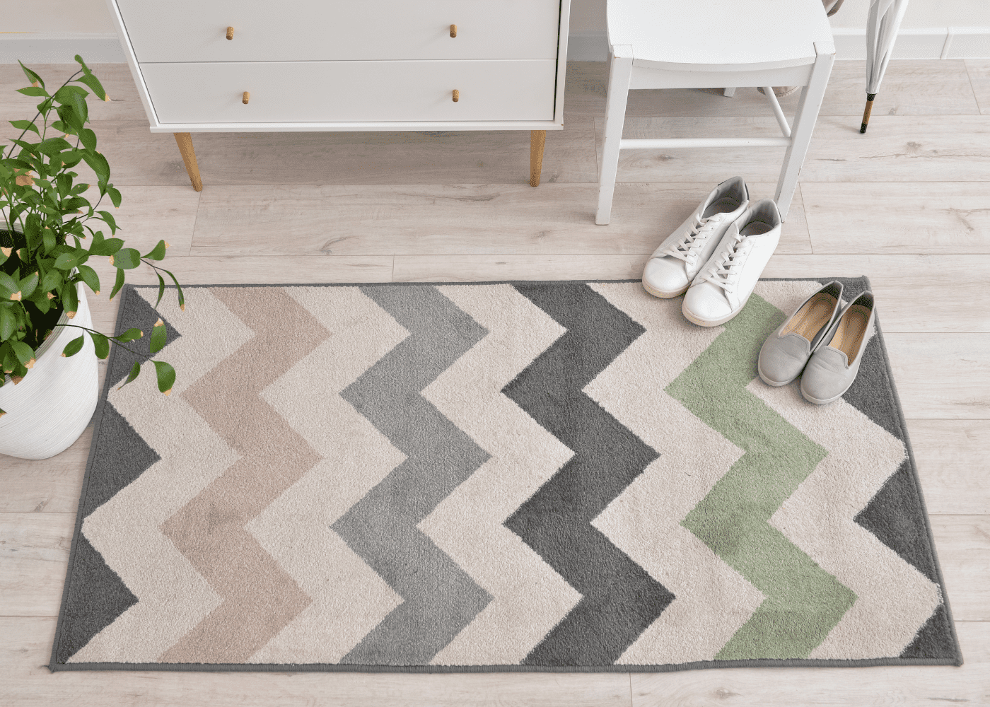A chevron style rug with pastel pink green and grey colors.