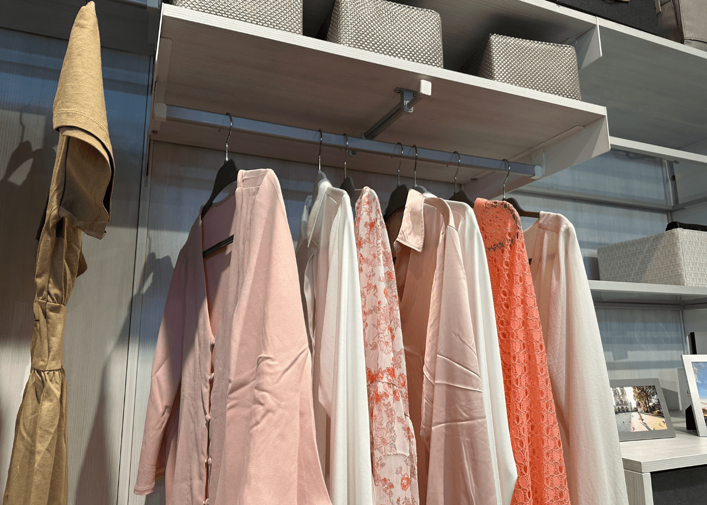 Clothing hanging on a bar in a small closet.