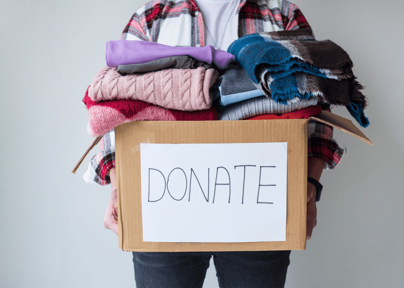 A box that says donate with towels and sweaters in it.