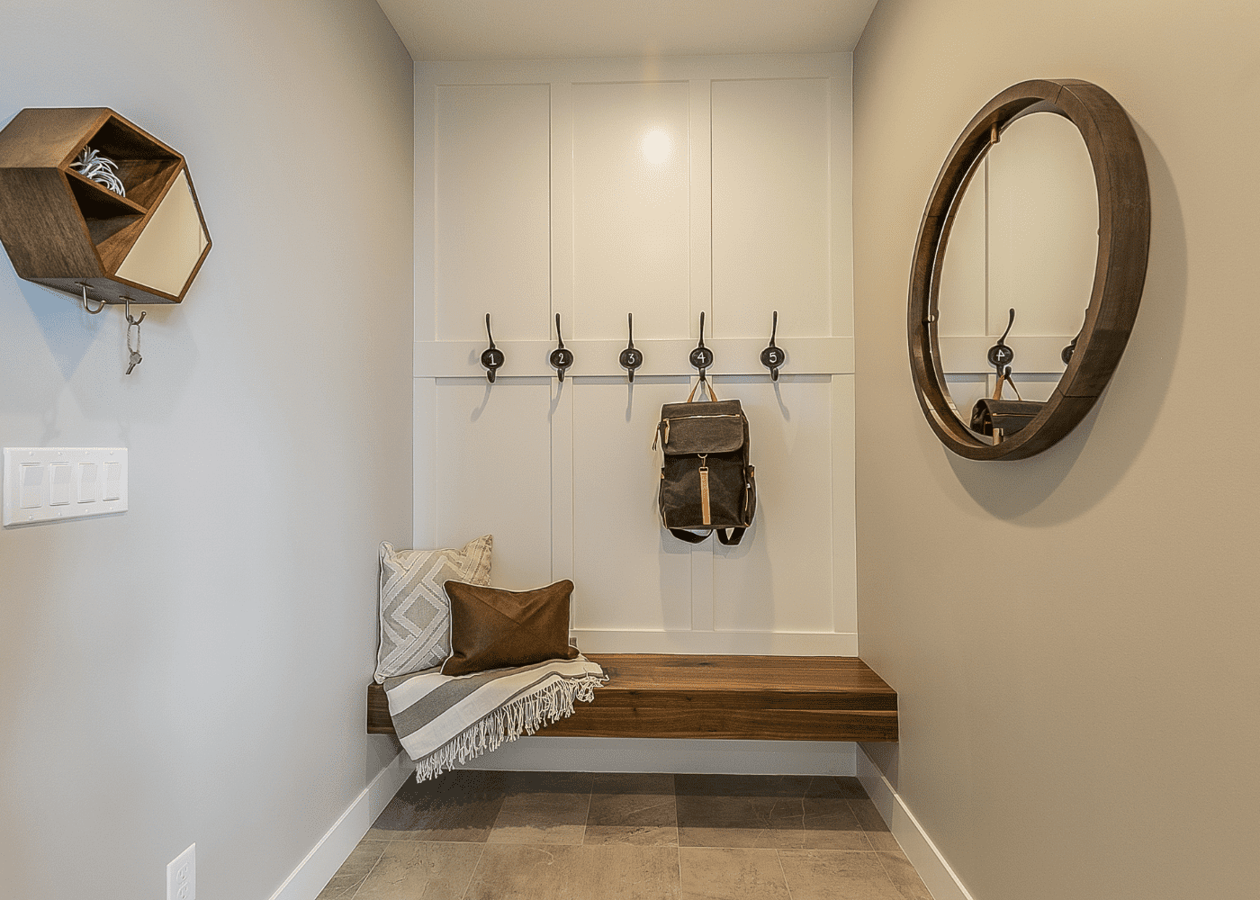 A mud room with a brown bench and a back pack hanging on the hook.
