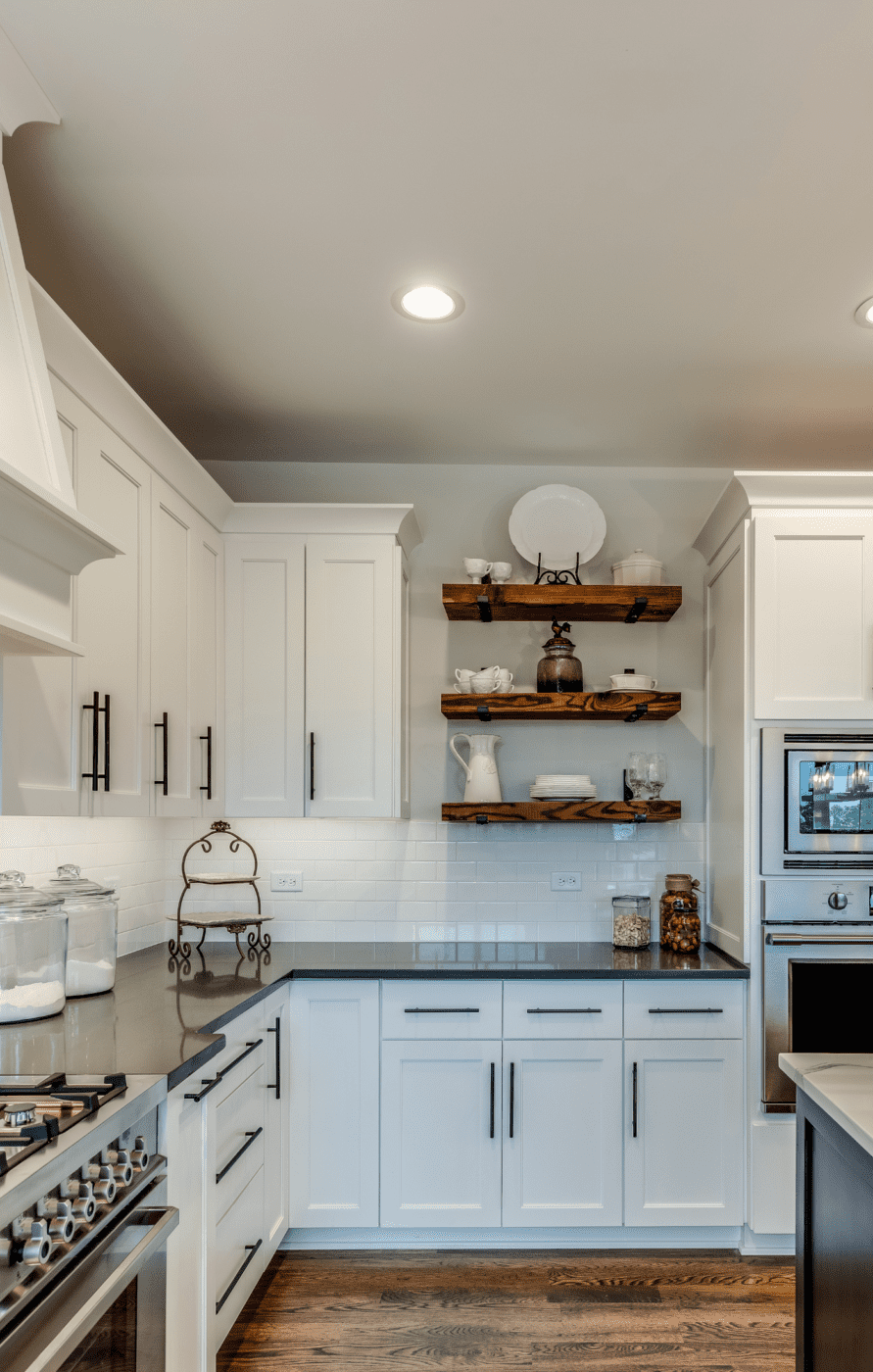 A white and black kitchen with a brown open shelving unit.