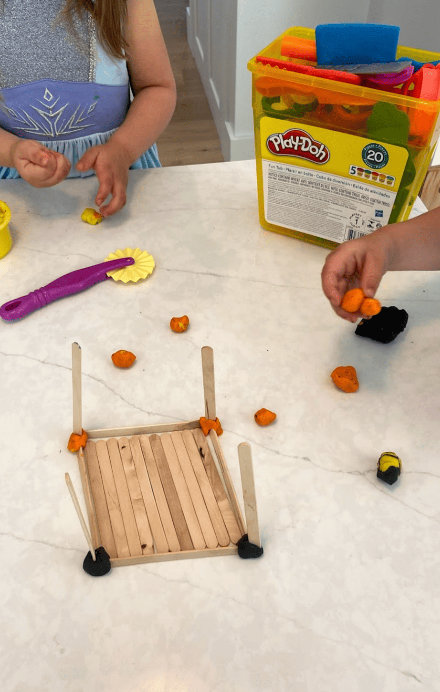 Toddler schedule building activity with playdoh and popsicle sticks.